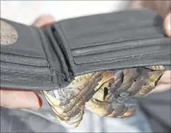  ??  ?? Scott Booth shows his charred wallet from the crash. He spent eight months in hospitals, including University Medical Center, before returning to his parents’ home.