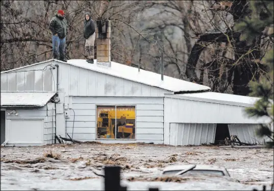  ?? Ben Lonergan The Associated Press ?? Nate Fuller and Archie Morrow await rescue on the roof of a home Thursday in Thorn Hollow outside of Adams, Ore.