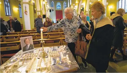  ?? ALASTAIR GRANT AP ?? Candles are lit next to a portrait of British lawmaker David Amess during a vigil for him at St. Michael’s Church in Leigh-on-Sea, England, on Sunday. Amess was killed on Friday during a meeting with constituen­ts at Belfairs Methodist Church in Leigh-on-Sea.