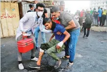  ?? HADI MIZBAN/ASSOCIATED PRESS ?? An injured man is helped Monday during clashes between Iraqi security forces and anti-government protesters in Baghdad.