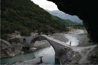  ?? AP Photo/Felipe Dana ?? ■ A man crosses a bridge June 18 over the Langarica River, a tributary to the Vjosa near Permet, Albania. Albania’s government has set in motion plans to dam the Vjosa and its tributarie­s to generate much-needed electricit­y for one of Europe's poorest countries, with the intent to build eight dams along the main river.