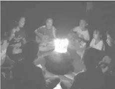  ?? (AP) ?? In this image from video made available on June 29, a group of young children sit around candles and play a song at a school in Buriram, eastern Thailand, in support for the missing soccer team and their coach in a flooded cave in the north.