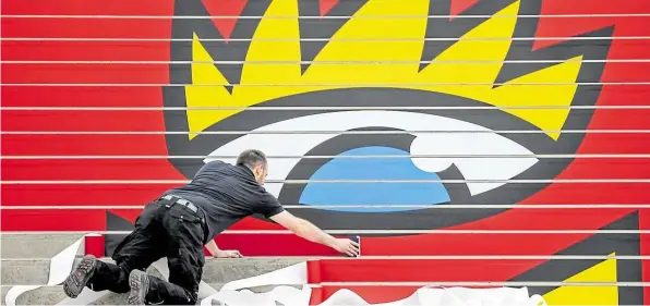  ?? DPA-BILD: JAN WOITAS ?? Immer sehenswert: Ein Mann beklebt Stufe für Stufe einer Treppe mit dem Logo der Leipziger Buchmesse in der Glashalle.