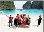  ?? AP/SAKCHAI LALIT ?? Tourists take selfies last week on the beach of Maya Bay on Thailand’s Phi Phi Leh island. The secluded bay has closed to visitors