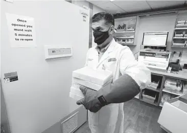  ?? CHRIS O’MEARA/AP ?? Ramon Docobo, assistant director of pharmacy, carries the COVID-19 vaccine Monday at Tampa General Hospital in Florida. “I feel like healing is coming,” said a critical care nurse who was inoculated in NewYork.
