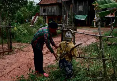  ??  ?? ABOVE: Cambodian farmer Sok Chany has posted two ‘Ting Mong’, armed with stocks, in front of her house in Trapeang Sla village in Kampong Province. BELOW: Ton Pheang puts the finishing touches to his second ‘Ting Mong’.