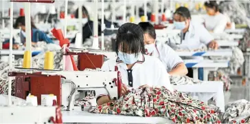  ?? — AFP ?? Hard times: Employees working at a textile factory in Anlong in China’s south-western Guizhou province. A weaker yuan risks stoking financial instabilit­y fuelled by capital outflows.