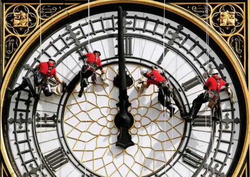  ??  ?? Time on their hands: Abseiling specialist­s inspect one of the four giant clock faces on Parliament’s Elizabeth Tower