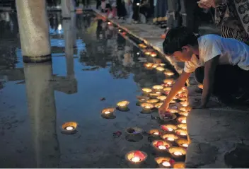  ?? Photos by Carlos Javier Sanchez / Contributo­r ?? Harish Venkat, 6, places a lighted candle at Tower of the Americas during the Diwali San Antonio Festival of Lights. Diwali is India's most important holiday.