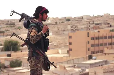  ?? ASSOCIATED PRESS FILE PHOTO ?? A fighter from the Syria Democratic Forces carries weapons and looks toward the northern town of Tabqa, Syria, on April 30. U.S.-backed Syrian forces say the battle for control of the Islamic State group’s de facto capital Raqqa, Syria, is imminent.