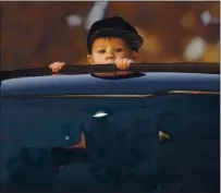  ??  ?? Hudson Martinez, 2, peeks through the sunroof of his family’s truck during the preview.