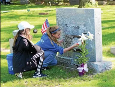  ?? TAWANA ROBERTS — THE NEWS-HERALD ?? All Saints of St. John Vianney School students clean veterans’ headstones at Mentor Cemetery on May 9.