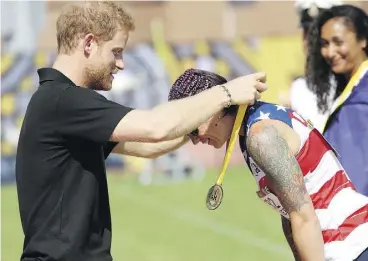  ?? CHRIS JACKSON / GETTY IMAGES FOR THE INVICTUS GAMES FOUNDATION ?? Prince Harry, who says his army experience helped him deal with his mother’s death, presents Christy Wise of the U.S. with the gold medal in athletics Sunday.