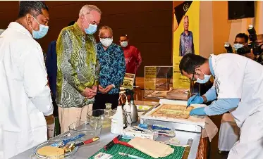  ?? — Bernama ?? Detailed work: Sultan Nazrin watching a demonstrat­ion of the process of restoring archival materials after launching the Perak National Archive of Malaysia building in Meru, Perak.