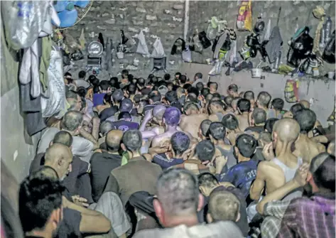  ?? BRAM JANSSEN/THE ASSOCIATED PRESS ?? Suspected Islamic State members sit inside a small room in a prison south of Mosul, Tuesday. Hundreds of suspected Islamic State members swept up by Iraqi forces in Mosul are being held in a cramped and stifling prison just outside the city.