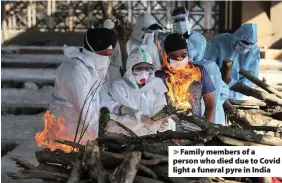  ??  ?? > Family members of a person who died due to Covid light a funeral pyre in India