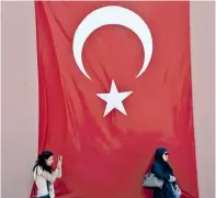  ??  ?? Μια γυναίκα βγάζει φωτογραφίε­ς με φόντο την τουρκική σημαία στην ιστορική συνοικία της Κωνσταντιν­ούπολης, Σουλταναχμ­έτ.