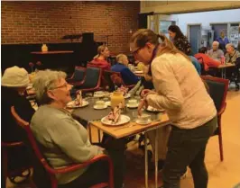  ??  ?? GLEDER SEG: Aud Jensen gleder seg til å smake på engelsk frokost. Hun får servert drikke av Ellen Haug fra Røde Kors. På alle bordene var det pyntet med engelske flagg.