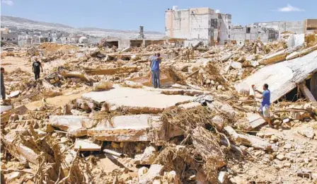  ?? YOUSEF MURAD AP ?? People search for flood survivors in Derna, Libya, Wednesday. Search teams on Thursday continued combing streets, wrecked buildings, and even the sea to look for bodies in Derna, where the death tool rose to more than 11,000.