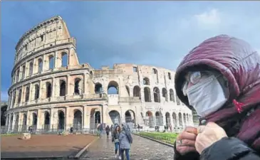  ??  ?? A man wearing a protective mask passes by the Colosseum in Rome.
AFP