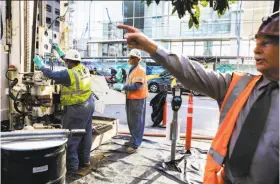  ?? Gabrielle Lurie / The Chronicle ?? Workers put equipment in place as part of tests they conducted on the Millennium Tower Monday. The luxury residentia­l high-rise in San Francisco has sunk at least 16 inches and is tilting to the northeast.