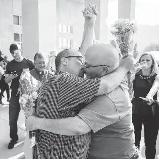  ?? ALTON STRUPP/THE COURIER-JOURNAL VIA THE ASSOCIATED PRESS ?? Michael Long, left, and Timothy Long kiss outside the Rowan County Judicial Center in Morehead, Kentucky, on Friday after becoming the second couple to receive a marriage licence a day after the county’s defiant clerk, Kim Davis, was taken to jail.