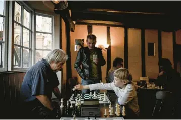  ?? MARY TURNER/THE NEW YORK TIMES ?? Maksym Kryshtafor, right, plays chess May 26 at the Eagle & Child pub in York, England. The 8-year-old boy and his mother fled to Romania following Russia’s invasion of Ukraine before ending up in Britain.