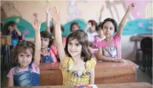  ?? — AFP ?? Syrian girls raises their hands during a class in their school in the rebelheld Eastern Ghouta town of Douma.