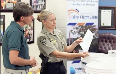  ?? / Ross Rogers ?? Brandy Womack (left), Floyd County Sheriff’s Office Community Posse, and Sgt. Carrie Edge look over the buckets assembled by students of the College and Career Academy for the RomeGaCare­s relief effort.