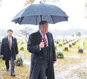  ?? PHOTOS: CAROLYN KASTER ?? Festive: President Donald Trump with first lady Melania during the Congressio­nal Ball in the grand foyer of the White House. Above right: President Trump visits Arlington Cemetery during ceremonies to remember veterans.