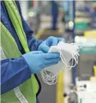  ?? KIMBERLY P. MITCHELL/USA TODAY NETWORK ?? James Varner, checks face masks at Warren Transmissi­on Operations plant in Warren, Mich.