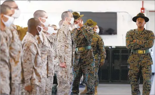  ??  ?? Although some coronaviru­s precaution­s are evident such as wearing face masks, drill instructor­s still get close to recruits to bark orders.