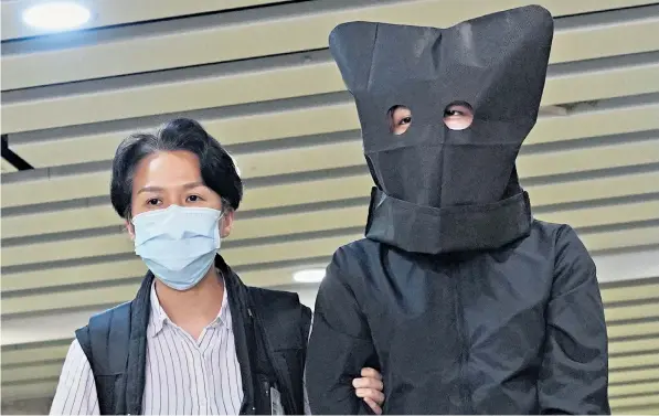  ??  ?? Above: a hooded suspect, accused of conspiring to publish ‘seditious material’, is escorted by a police officer to search for evidence. Left: an officer inspects a page from one of the books on screen