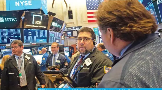  ??  ?? NEW YORK: Traders work on the floor at the opening bell of the Dow Industrial Average at the New York Stock Exchange on Friday in New York. — AFP