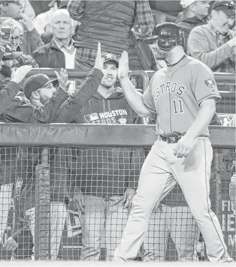  ?? Stephen Brashear / Getty Images ?? Astros designated hitter Evan Gattis (11) is congratula­ted by teammates during a break in play after hitting a two-run double during the seventh inning of Wednesday night’s game against the Mariners in Seattle. Gattis’ double helped the Astros secure a...