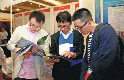  ?? ZHANG CHENG / XINHUA ?? Graduates look through job descriptio­ns at an employment fair held in Beijing in April.