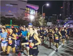  ?? Miami Herald/tns ?? The 18th annual Life Time Miami Marathon and Half Marathon runners take off in the dark at 6 a.m. Sunday, Feb. 9, 2020 in front of Americanai­rlines Arena. There were more than 20,000 combined runners registered for the marathon and half marathon.