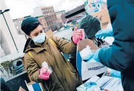  ?? JOSE A. ALVARADO JR./THE NEW YORK TIMES ?? New U.S. coronaviru­s cases have dropped by 21% in the last two weeks. Above, volunteers hand out face masks Monday in New York City.