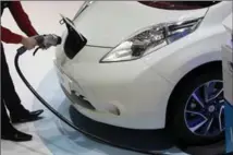  ?? BLOOMBERG FILE PHOTO ?? An employee installs a charging plug in the socket of a Nissan Leaf.