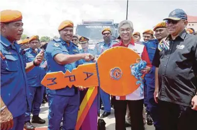  ?? [FOTO MUHAIZAN YAHYA/BH] ?? Ahmad Zahid menyerahka­n replika kunci Logistik Operasi APM Bagan Datuk kepada Pegawai Pertahanan Awam Daerah Bagan Datuk, LT (PA) Mohd Zaidi Ahmad (dua dari kiri). Yang turut hadir Shahidan (kanan) dan Azmy (kiri) pada majlis Program Timbalan Perdana Menteri Bersama Warga APM Bagan Datuk di Sekolah Menengah Sains Bagan Datuk, semalam.