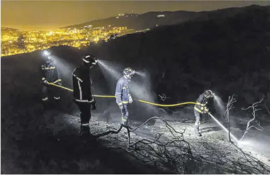  ?? Jordi Otix ?? Un grupo de bomberos sofocan los últimos restos calientes del incendio declarado la tarde del martes en Collserola.