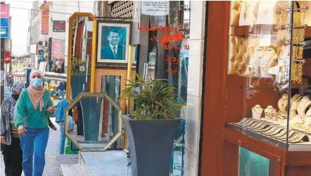  ?? KHALIL MAZRAAWI AFP VIA GETTY IMAGES ?? Women walk past a store displaying a portrait of Jordanian King Abdullah II in Amman on Monday. Jordanian authoritie­s had accused the king’s half-brother, Prince Hamzah, of being involved in a “malicious plot” to destabiliz­e the country’s security.