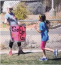  ??  ?? Liz Williams encourages runners as they complete laps of their school’s field as they run a 5K.