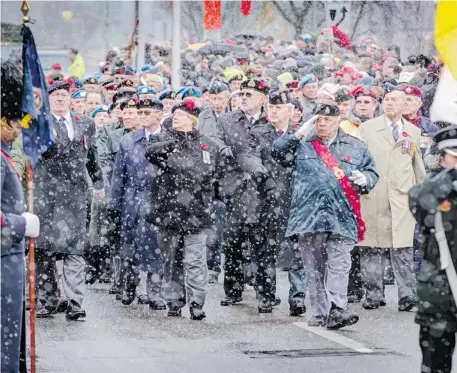  ?? Photos: Chris Mikula/Postmedia News ?? A veterans’ parade marches past during the snowy Remembranc­e Day ceremonies at the National War Memorial in Ottawa on Monday.