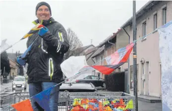  ?? FOTO: S. FUCHS ?? Vom Wetter recht unbeeindru­ckt: Joachim Weber spannt auf dem Anhänger die Seile mit den bunten Wimpeln.