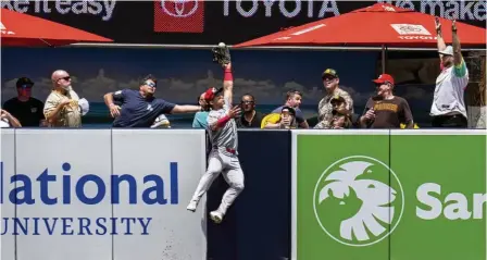  ?? GREGORY BULL / AP ?? Cincinnati Reds center fielder Stuart Fairchild makes a leaping catch over the wall for the out on a deep fly ball hit by the Padres’ Manny Machado during the first inning Wednesday in San Diego.