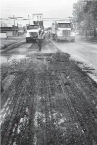  ?? Photo by Les Minor ?? ■ Work on West Seventh Street downtown as seen last week through a fog of dust that a sweeper kicked up in front of the “mill and inlay” process.