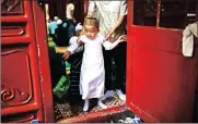  ?? Picture: REUTERS ?? A HELPING HAND: A man guides a child through the door of the prayer hall during celebratio­ns at the historic Niujie mosque in Beijing, China, yesterday.