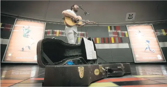  ?? PIERRE OBENDRAUF ?? Métro musicians like Greg Halpin secure spots on a first-come, first-served basis, writing their names and desired time slot on a piece of paper. The schedule is placed behind an STM sign featuring a lyre, which symbolizes a designated area for...