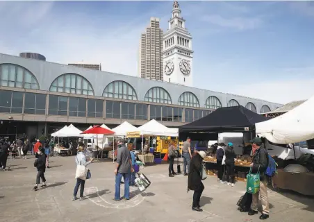  ?? Photos by Paul Chinn / The Chronicle ?? Signs urge social distancing throughout the the Ferry Plaza Farmers Market, which will get more crowded as summer nears.